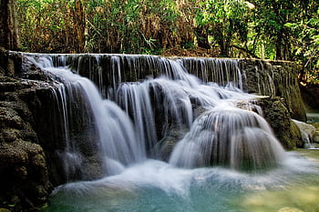 A tranquil waterfall cascading in a lush forest, captured with a long exposure. HD wallpaper