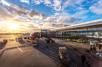 A vibrant sunset at Copenhagen Airport with airplanes and bustling activity. HD wallpaper