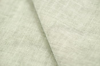 A close-up view of a soft, light-colored linen fabric displaying its intricate texture and weave. HD wallpaper
