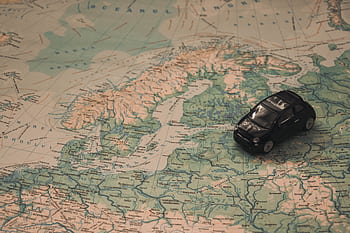A miniature black car on a detailed map of Scandinavia, symbolizing travel adventures. HD wallpaper