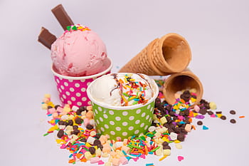 Delicious ice cream in vibrant cups with scattered sprinkles and waffle cones. HD wallpaper