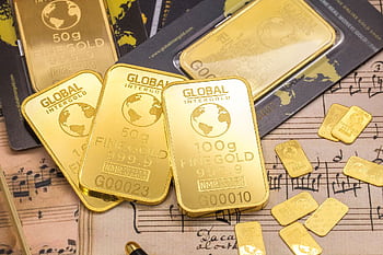 Gold bars stacked on sheet music, showcasing wealth and luxury with fine detail. HD wallpaper