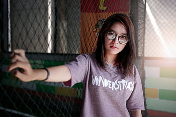 Portrait of a young woman wearing eyeglasses and a 'Wonderstruck' t-shirt posing indoors. HD wallpaper