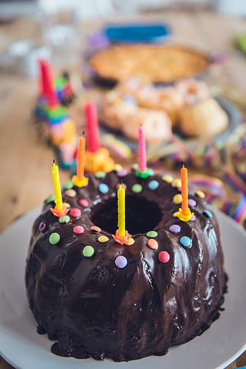 A delicious chocolate cake decorated with colorful candles and sprinkles, ready for a birtay celebration. HD phone wallpaper