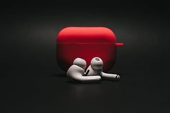 Sleek white earbuds with modern red case on a dark surface, highlighting stylish audio technology. HD wallpaper