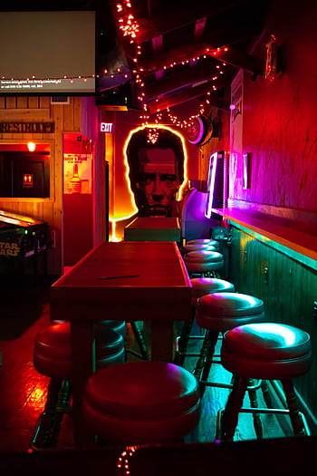 Vibrant neon-lit bar with artistic decor and empty seating, creating an inviting and modern atmosphere. HD phone wallpaper