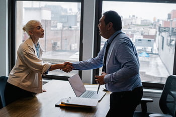 Professional handshake between two colleagues in a modern office setting. HD wallpaper