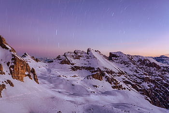 Breathtaking view of the snow-covered Dolomites under a purple twilight sky with star trails. HD wallpaper