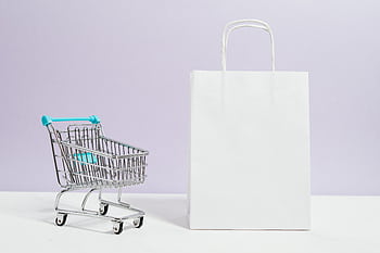 Minimalist of a white shopping bag and mini cart on a soft pastel background. HD wallpaper