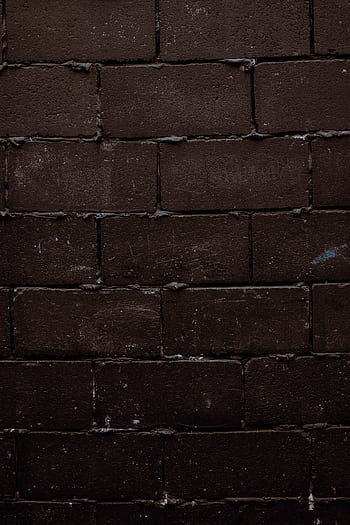 Close-up texture of a dark, rough brick wall, perfect for backgrounds. HD phone wallpaper