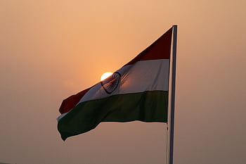 The Indian national flag waves majestically against a sunset backdrop, symbolizing patriotism in Lucknow. HD wallpaper