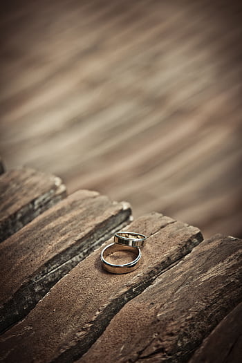 Close-up of elegant silver wedding rings on a rustic wooden surface, symbolizing love and unity. HD phone wallpaper