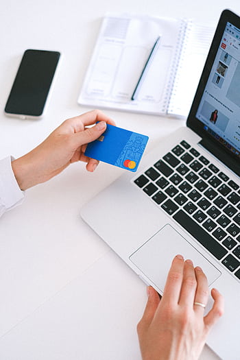 Person making an online purchase with a credit card on a laptop, showcasing modern ecommerce technology. HD phone wallpaper