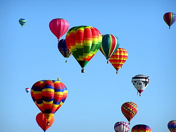 Colorful hot air balloons floating in a clear blue sky, showcasing a vibrant festival scene. HD wallpaper