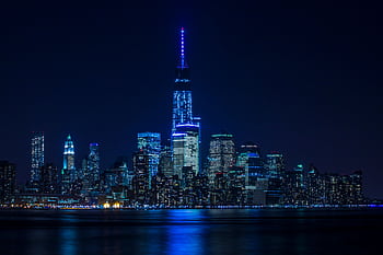 Illuminated New York City skyline reflecting over the Hudson River at night. HD wallpaper
