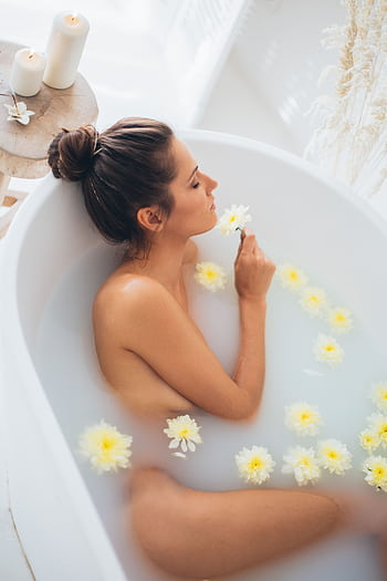 Elegant woman enjoying a relaxing flower bath, capturing luxury and wellness indoors. HD phone wallpaper