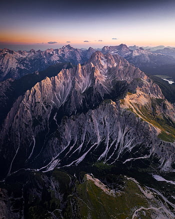 A breathtaking aerial view of a rocky mountain range under twilight skies, showcasing natural beauty and tranquility. HD phone wallpaper
