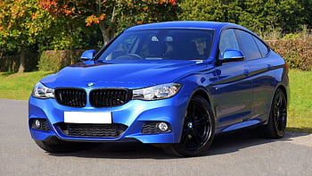 Modern blue luxury car parked by a scenic roadside on a sunny day. Stylish design. HD wallpaper