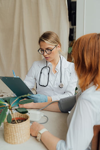 A female doctor checks a patient's blood pressure during a routine consultation in a clinic. HD phone wallpaper
