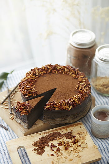 A delicious homemade chocolate cake topped with almonds, surrounded by baking ingredients and a cup of tea. HD phone wallpaper