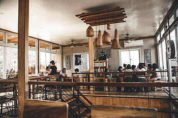 A modern café interior featuring a group dining, wooden decor, and natural lighting. HD wallpaper