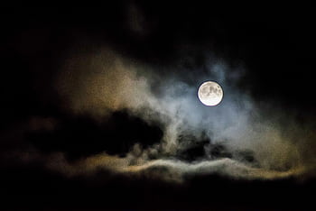 A full moon illuminates the night sky, shrouded by eerie clouds creating a spooky atmosphere. HD wallpaper