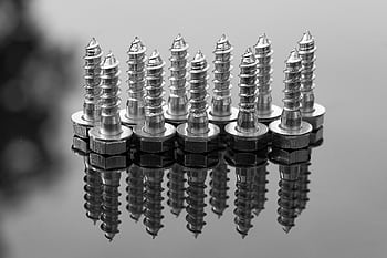 Close-up of shiny metal screws reflecting on a glossy surface. Ideal for industrial or construction themes. HD wallpaper