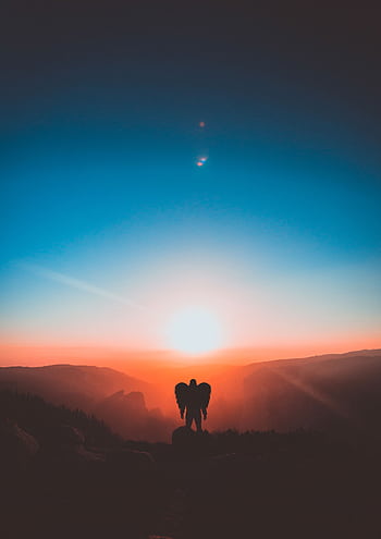 A mesmerizing sunset with silhouette of a person with wings, capturing a serene and ethereal moment. HD phone wallpaper