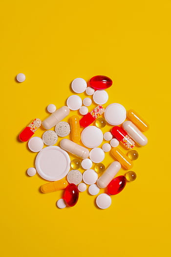 A collection of diverse tablets and capsules on a vibrant yellow background, symbolizing healthcare and medication. HD phone wallpaper