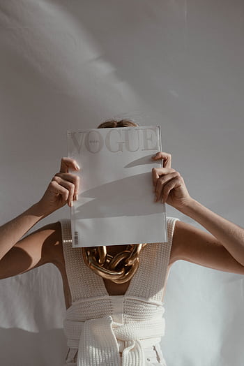 Fashionable woman covers her face with Vogue magazine, showcasing style and elegance. HD phone wallpaper
