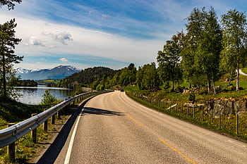 Beautiful road by a lake with mountains and trees in Hol, Norway, under a blue sky. HD wallpaper
