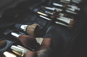 A stylish arrangement of makeup brushes set against a dark, elegant background. HD wallpaper