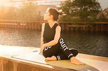 Woman practicing yoga at sunset by a serene river in Gamla Staden, Sweden. HD wallpaper