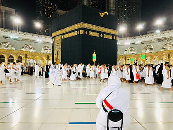 Muslim pilgrims perform Tawaf around the Kaaba in Mecca under bright lights at night. HD wallpaper