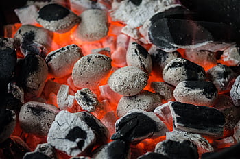 Close-up of glowing charcoal briquettes ready for outdoor barbecue grilling. HD wallpaper
