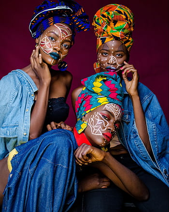Three women in colorful African outfits with face paint and headdresses celebrating culture. HD phone wallpaper