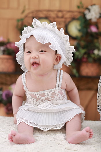 Cute baby girl wearing a lace dress and hat, smiling happily indoors. HD phone wallpaper