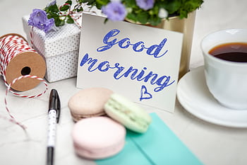 Good morning card with coffee, macarons, and gifts creating a cozy scene. HD wallpaper
