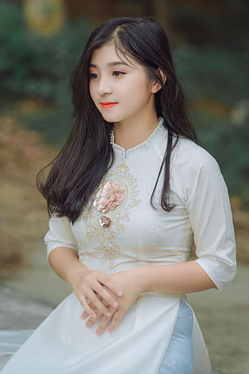 Beautiful young woman in a traditional dress posing outdoors, showcasing a serene and elegant fashion style. HD phone wallpaper