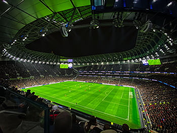 A captivating night football match at a packed stadium in England, showcasing dynamic gameplay and vibrant atmosphere. HD wallpaper