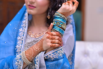A bride showcases intricate henna designs and vibrant jewelry in traditional attire. HD wallpaper