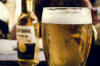 Close-up of chilled beer with frothy head next to a bottle on a bar table. HD wallpaper