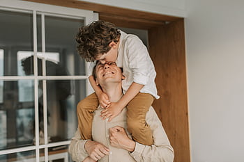 A joyful moment of a father carrying his son on his shoulders indoors. HD wallpaper