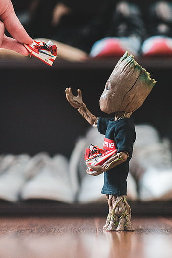Adorable toy character receiving miniature sneakers, showcasing playful creativity. HD phone wallpaper