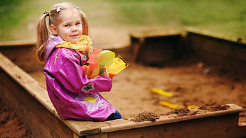 Cute Little Girl With Toys Is Wearing Pink Raincoat Sitting On Wood Bench In Blur Background Cute HD wallpaper