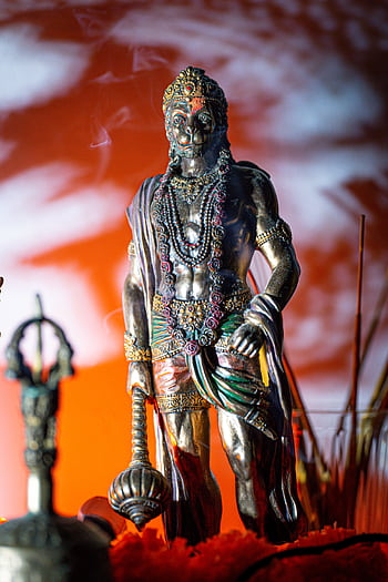 A detailed statue of Lord Hanuman against a dramatic, colorful background. HD phone wallpaper