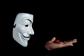 Side view of an anonymous mask facing a hand holding a red flower against a black background. HD wallpaper