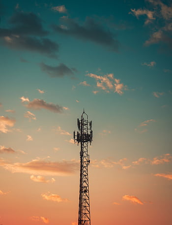 A communication tower silhouetted against a colorful sunset sky in Cruzeiro, Brazil. HD phone wallpaper