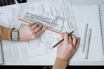 An architect uses a ruler and pencil on blueprints, showcasing workspace and planning. HD wallpaper