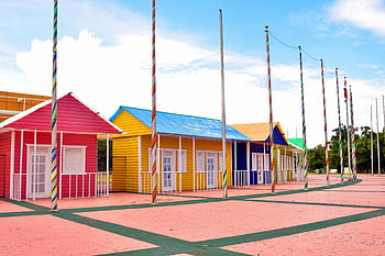 Brightly painted houses with flag poles under clear skies. Ideal for architecture and travel themes. HD wallpaper